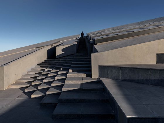 The Ascent — Worm's-eye on the stair — a lone figure at the crest